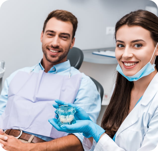 Stomatolog pokazuje pacijentu model zubnog implanta tokom konsultacije