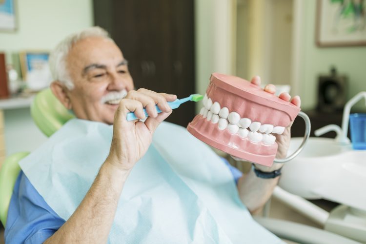 stariji muskarac u zubarskoj ordinaciji za nameštanje zubnih proteza