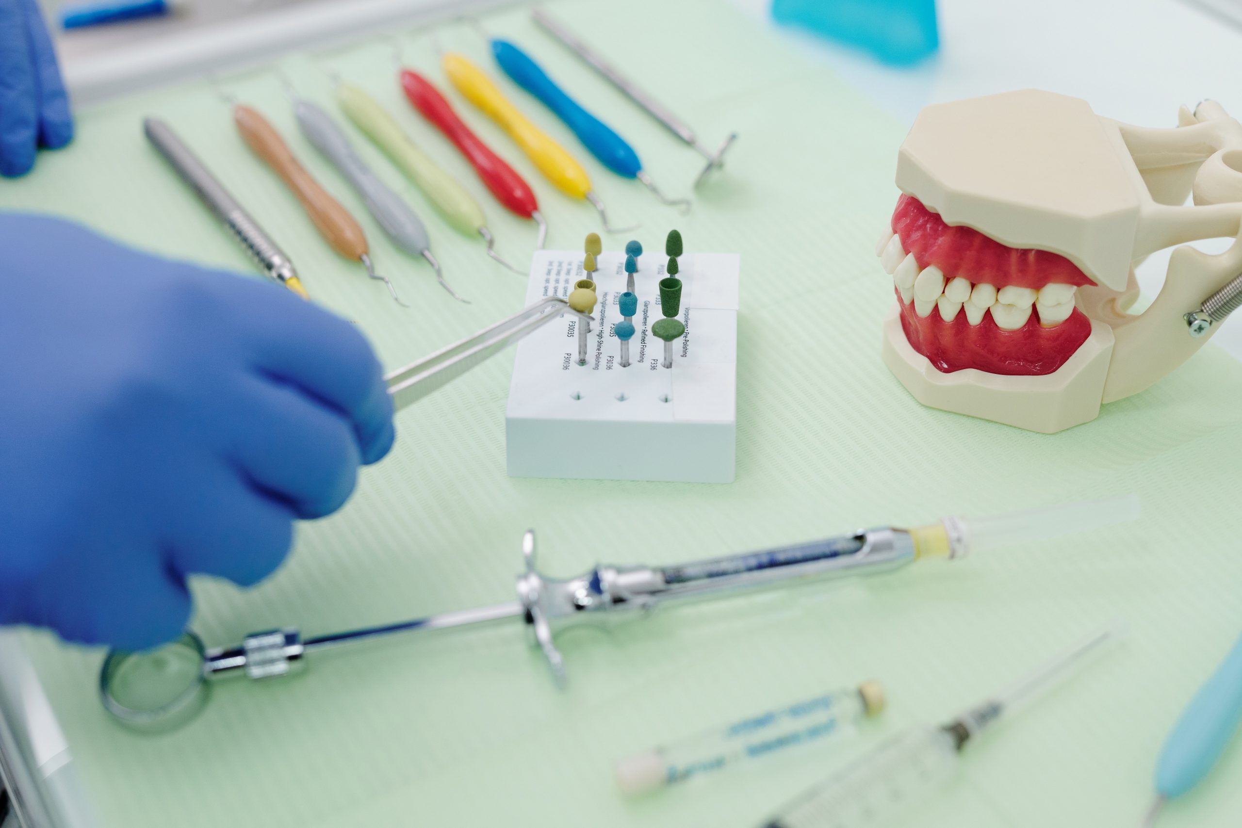 stomatolog sa plavom rukavicom uzima jedan od zubarskih intrumenata sa police