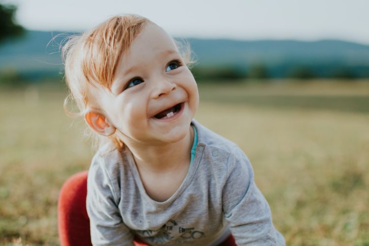 jednogodisnja beba se osmehuje sa dva mlecna zubica